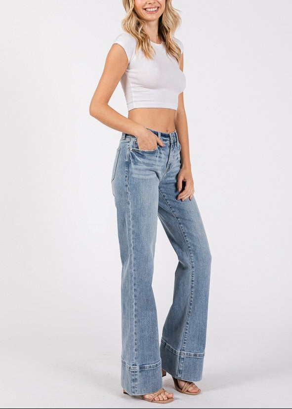 Close-up and full-length views of high-rise wider leg jeans with exaggerated trouser hem in a light/medium wash denim.