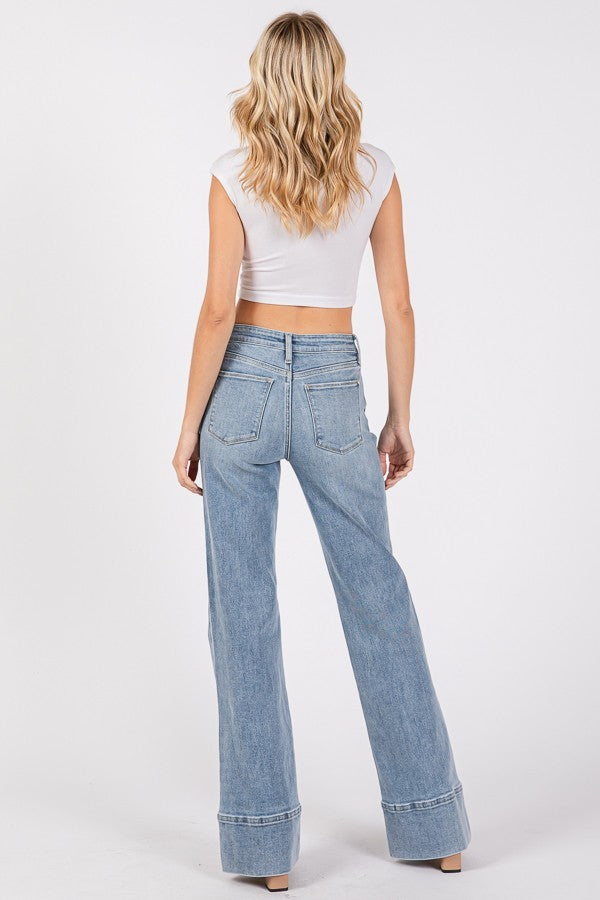 Close-up and full-length views of high-rise wider leg jeans with exaggerated trouser hem in a light/medium wash denim.