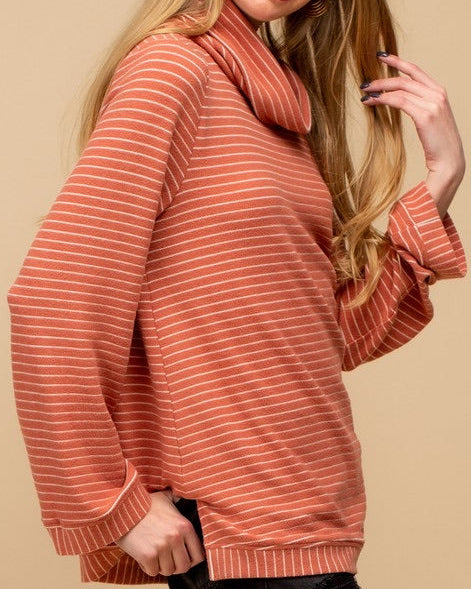 Woman wearing a salmon-colored striped sweater against a beige background