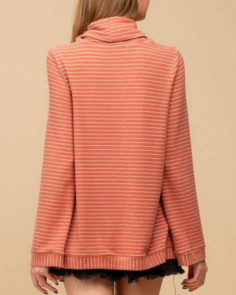 Person wearing a salmon-colored striped sweater against a beige background.