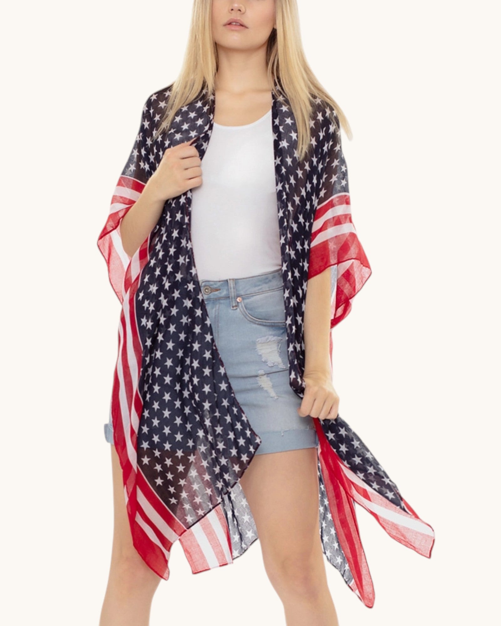 Woman wearing an American flag patterned kimono / cover up over a white top and denim shorts on a white background.