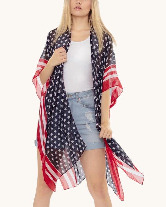 Woman wearing an American flag patterned kimono / cover up over a white top and denim shorts on a white background.