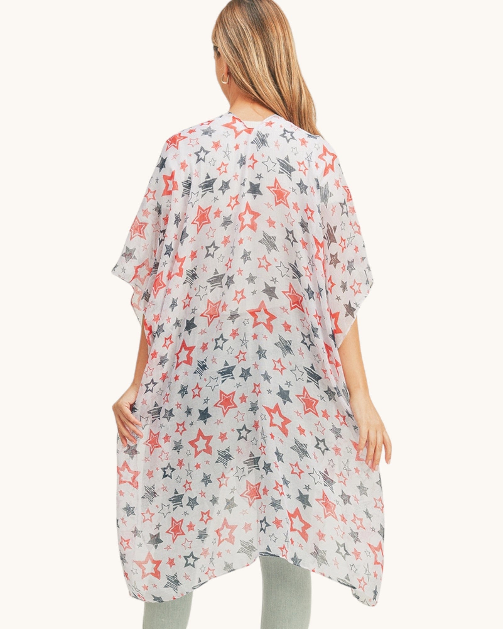 Back view of a woman wearing a star-patterned kimono-style garment over jeans on a white background.