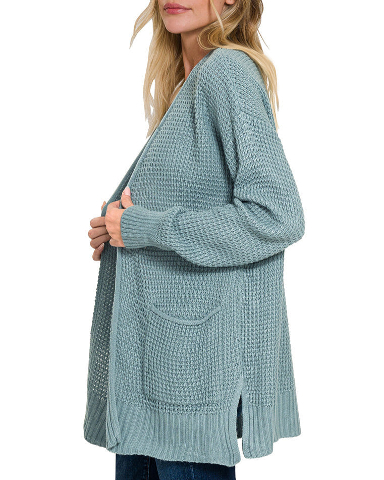 Woman wearing a blue-grey cardigan on a white background.