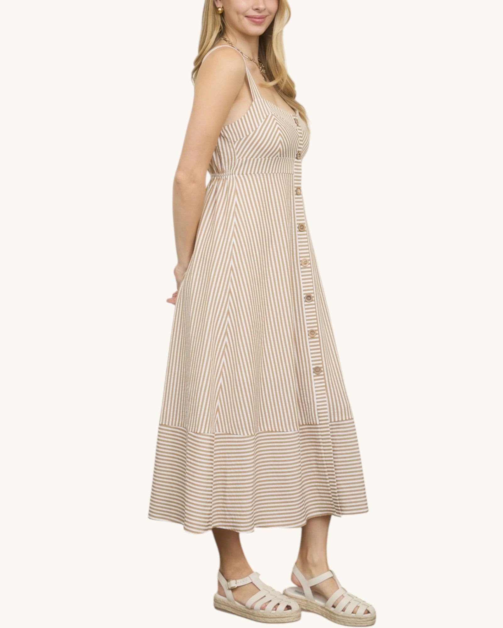 Side view of a woman wearing a beige striped dress on a white background.