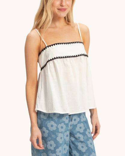 Woman wearing a white tank top with black trim on a white background.