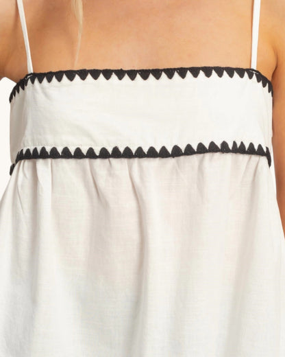 Close up of a white tank top with black trim on straps and hem.