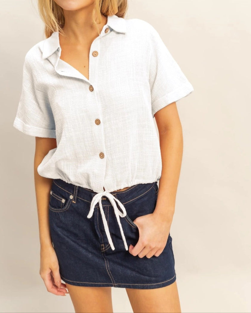 White short sleeve cotton button-up shirt with drawstring hem.