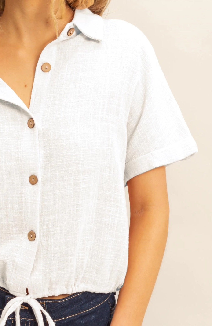 White short sleeve cotton button-up shirt with drawstring hem.