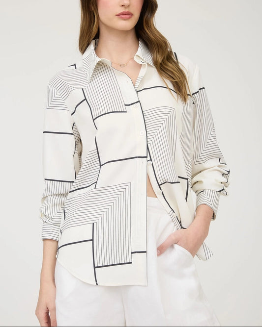 Woman wearing a B&W geometric patterned shirt with a plain background.