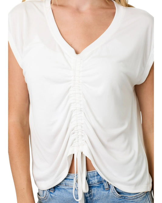 White sleeveless top with tie bottom ruche detail worn by a person on a white background.