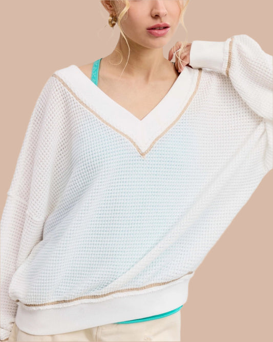 Woman wearing a white textured waffle knit long sleeve top.
