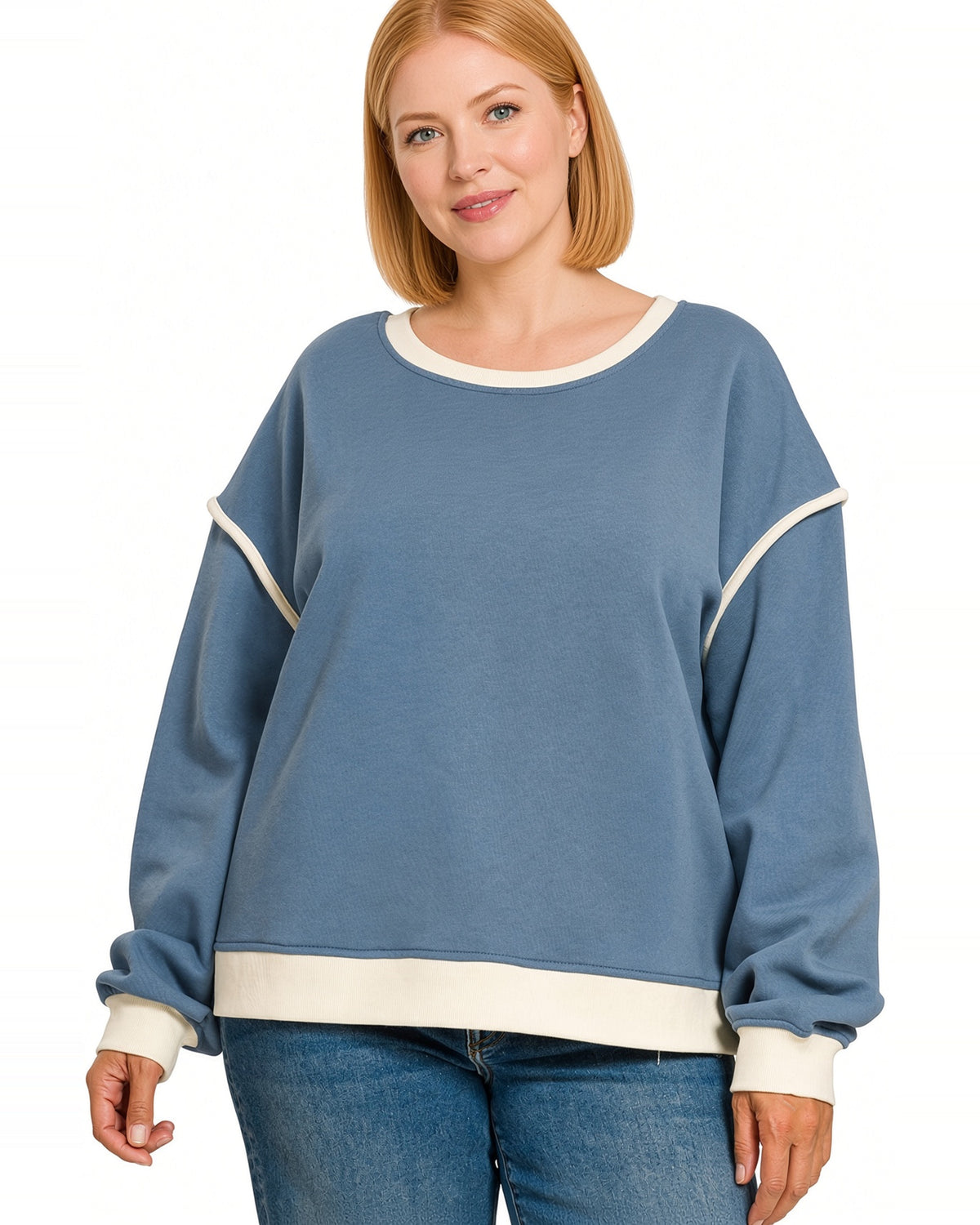 Woman wearing a blue pullover sweatshirt with a round neckline and contrast ivory trim on hem, neckline and cuffs.