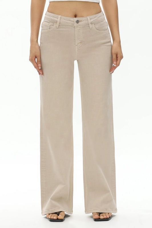 A model from the waist down wearing a pair of light beige wide-leg jeans, paired with black flat sandals, against a plain white studio background.