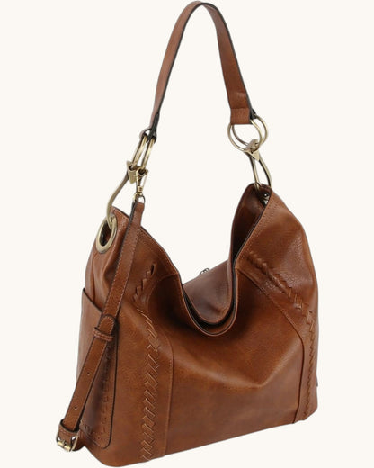 Brown leather hobo handbag with bronze hardware on a white background.