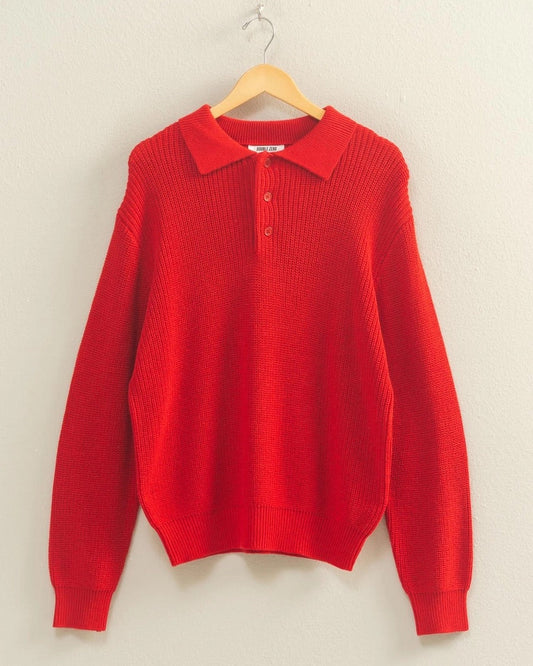 Red sweater on a hanger against a beige wall