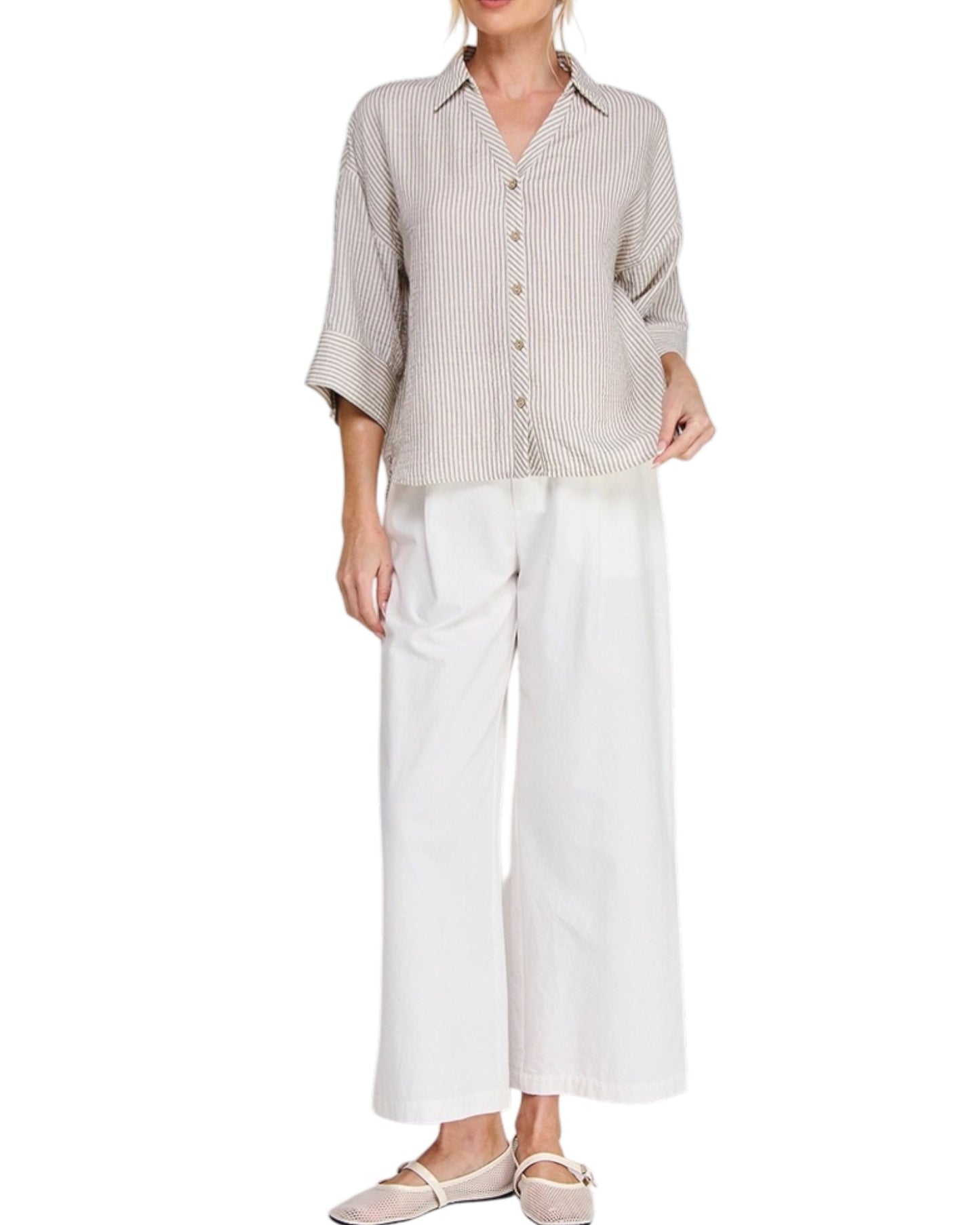 Woman wearing a beige striped shirt and white pants on a white background.