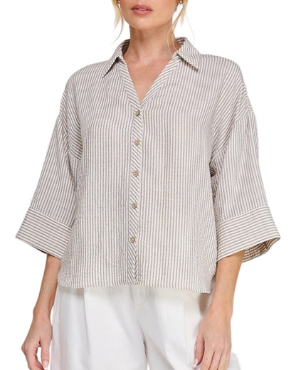 Woman wearing a striped shirt with 3/4 sleeves on a white background.