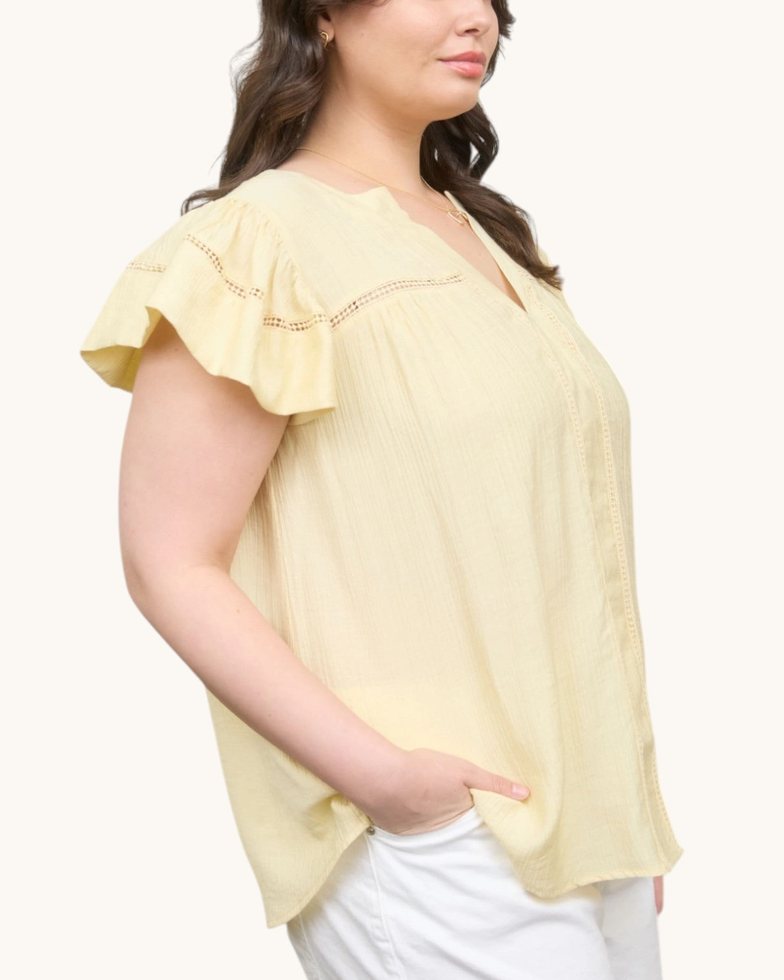 Pale yellow V-neck top with ruffle sleeve, side view.