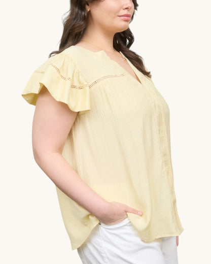Pale yellow V-neck top with ruffle sleeve, side view.