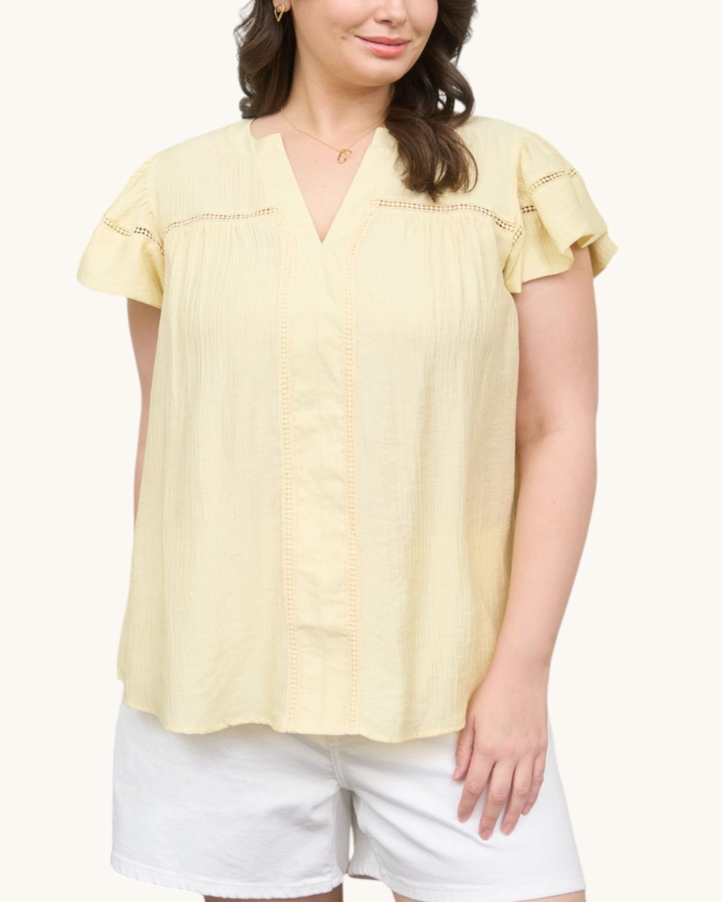 Woman wearing a Pale yellow V-neck top with ruffle sleeve, front view.