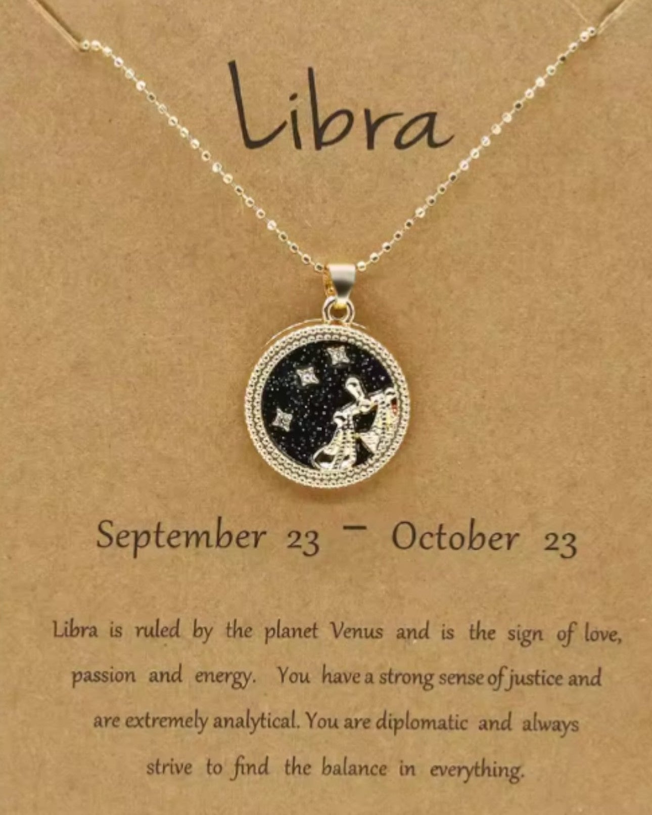 Necklace with Libra zodiac symbol on a brown card with text.