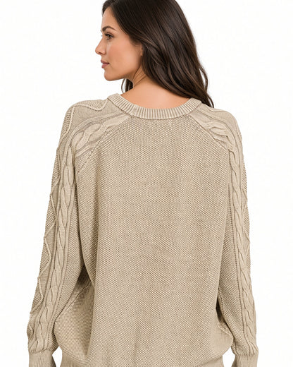 A woman shown from the back wearing a beige cable-knit sweater against a plain white background.