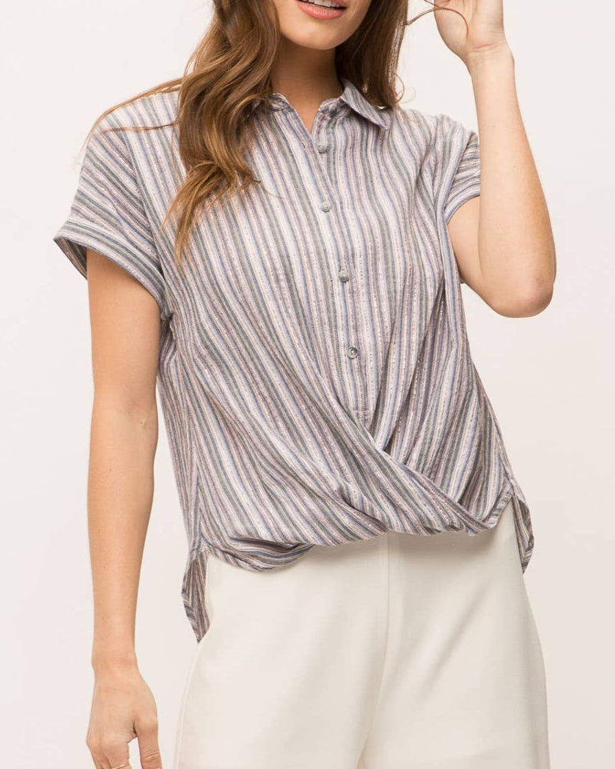 Woman wearing striped short sleeve button-up shirt with wrap front drape, collar and gold lurex detail.