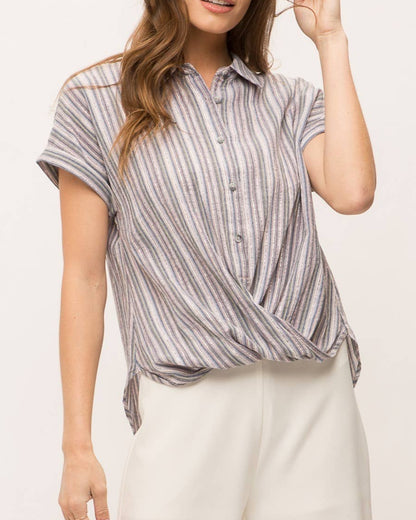 Woman wearing striped short sleeve button-up shirt with wrap front drape, collar and gold lurex detail.