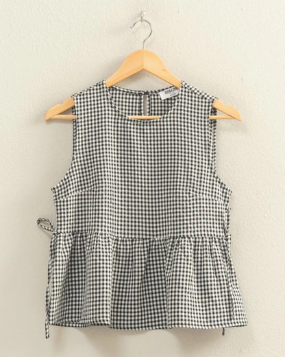 Black and white checkered sleeveless top on a hanger against a beige background