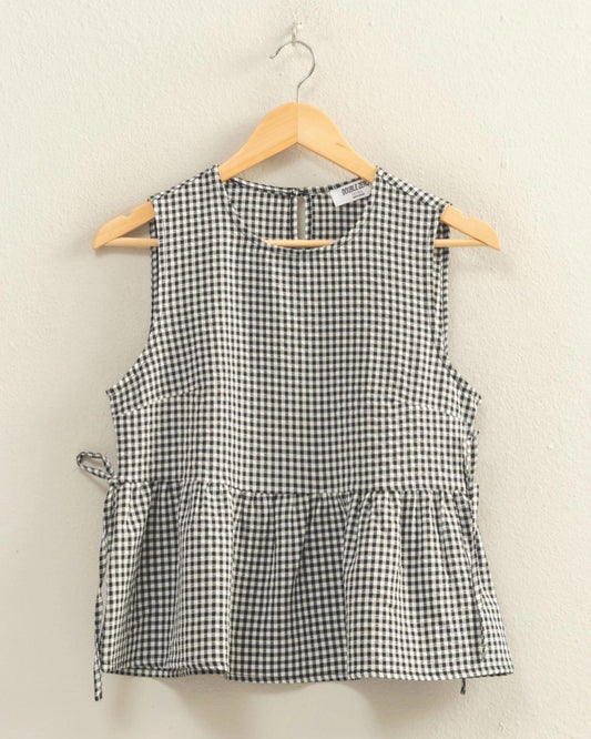 Black and white checkered sleeveless top on a hanger against a beige background