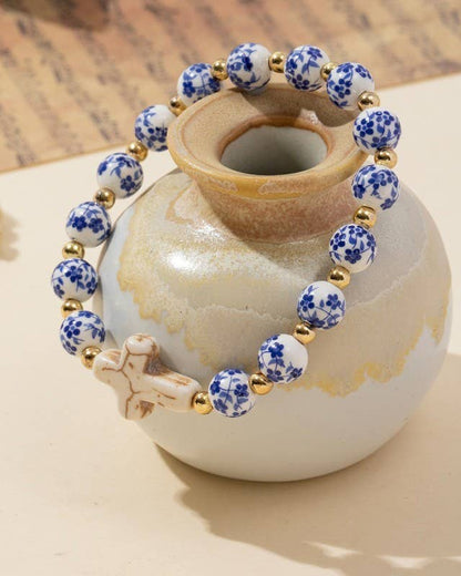 Bracelet with blue and white beads and gold accents on a small ceramic vase.