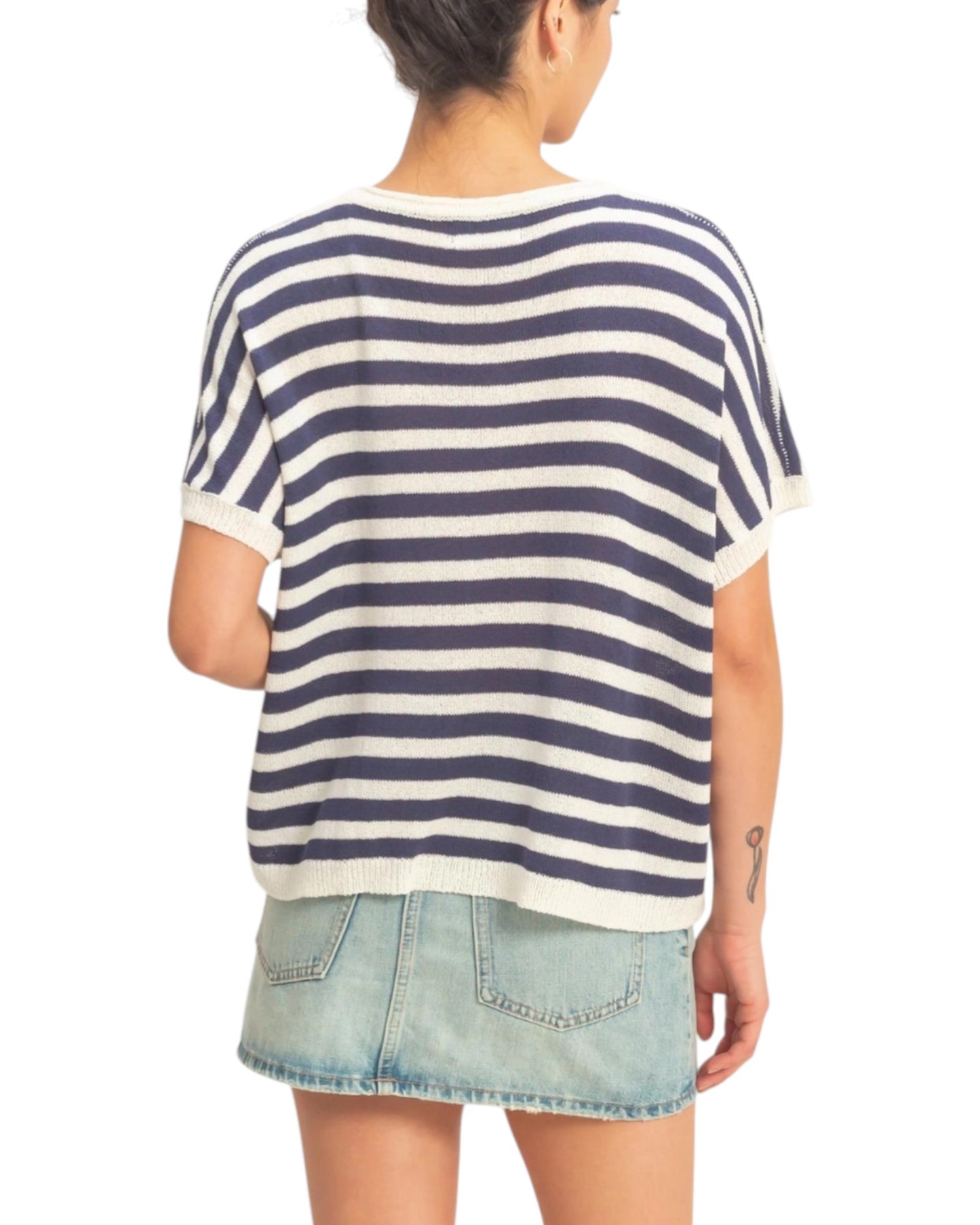 Person wearing a navy and white striped shirt with denim shorts on a white background.
