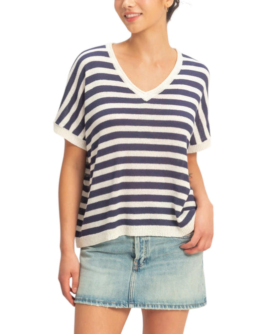 Person wearing a navy and white striped shirt with denim skirt on a white background.