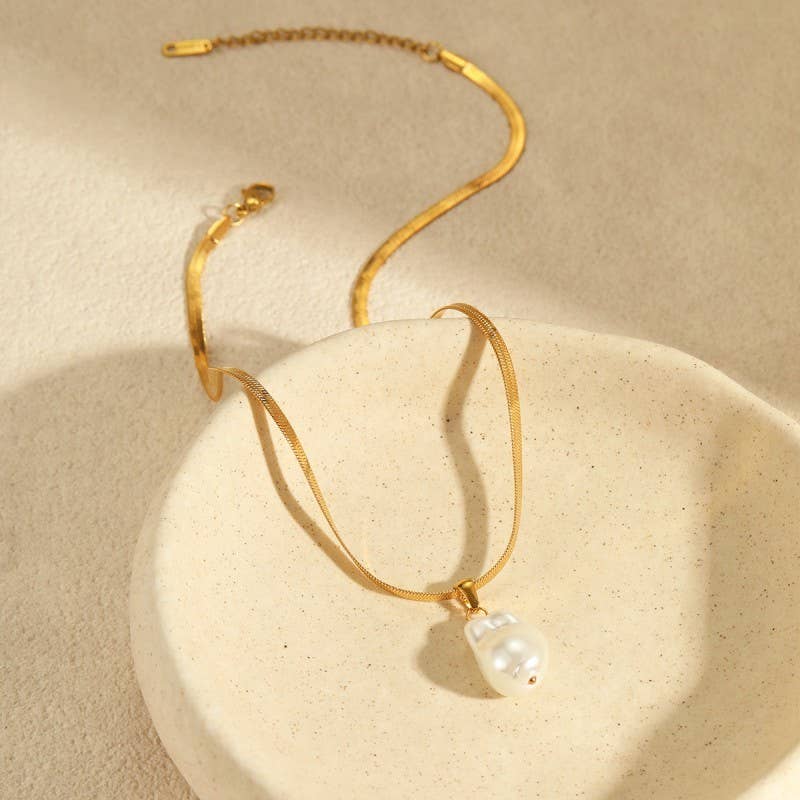 Gold necklace with a pearl pendant on a beige background