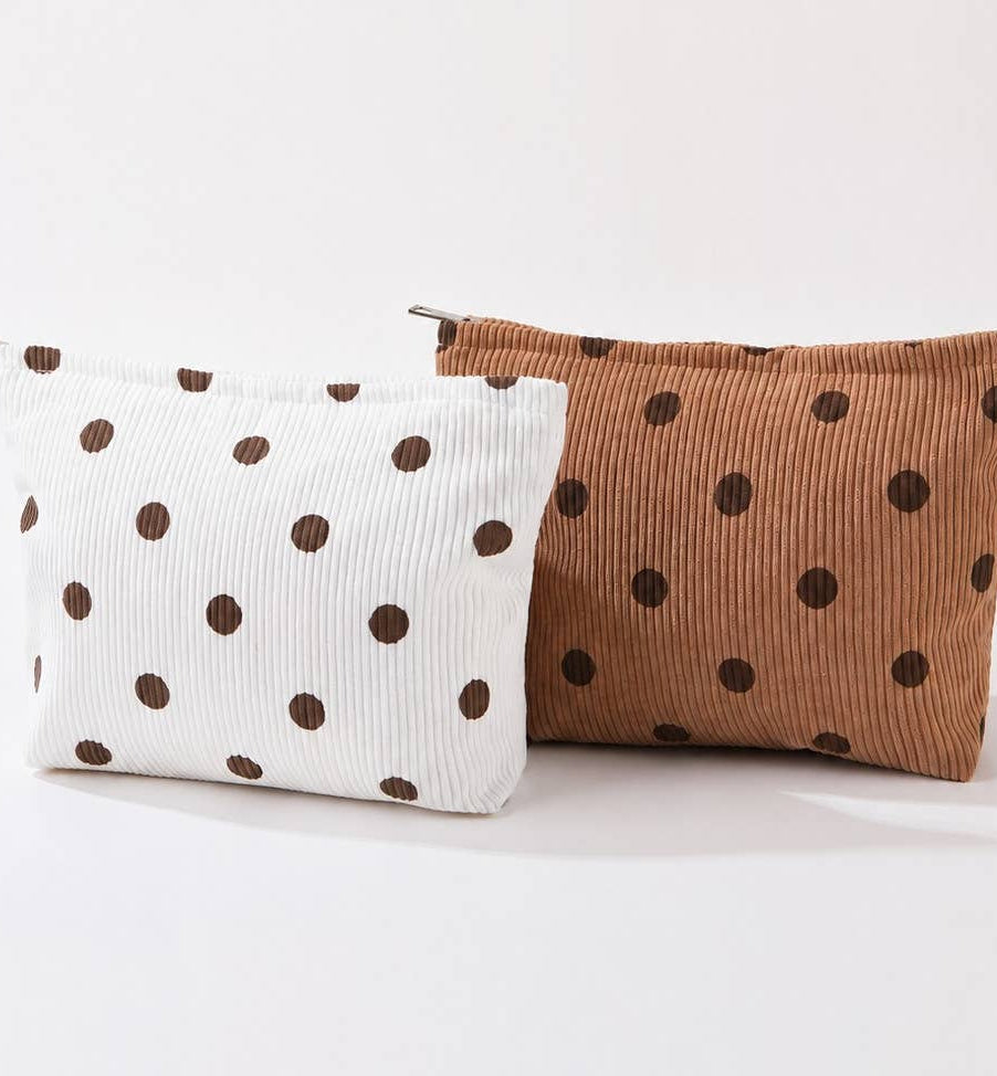Two polka dot make-up bags, one white with brown dots and one brown with dark brown dots, on a light background.