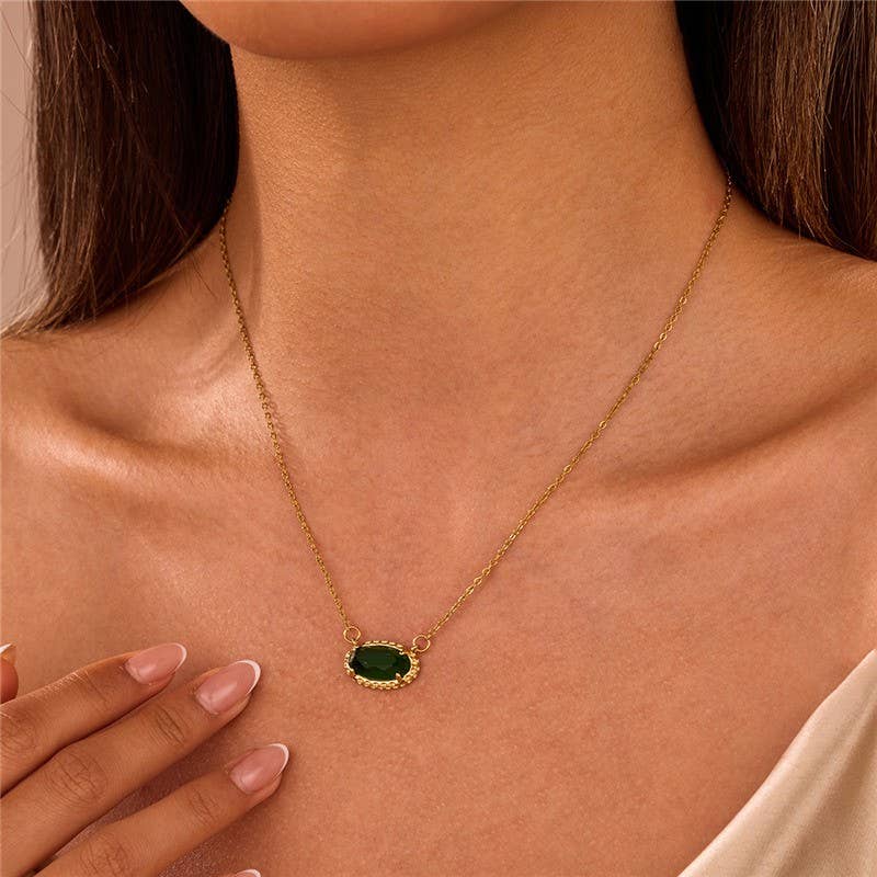 Woman wearing a gold necklace with a green emerald oval pendant.