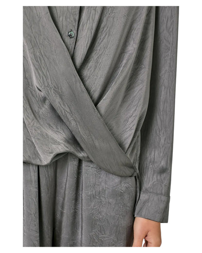 Woman wearing a grey button up crinkle satin twist front blouse. 