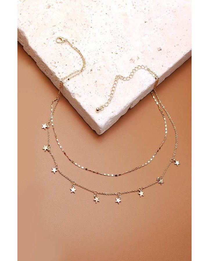 Gold necklace with star pendants on a textured surface.