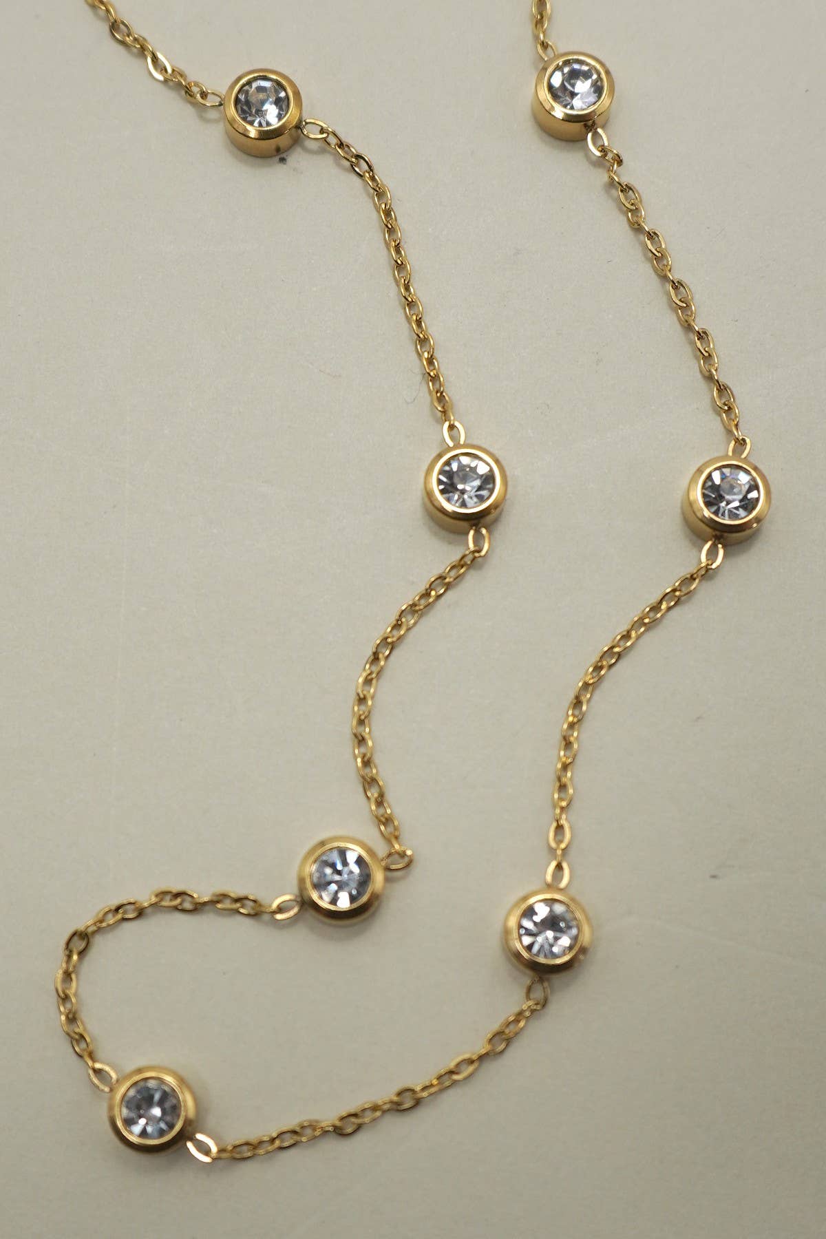 Gold necklace with diamond-like stones on a beige background