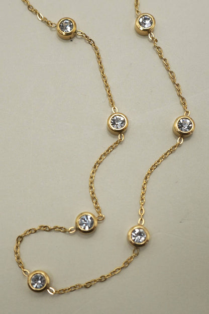 Gold necklace with diamond-like stones on a beige background