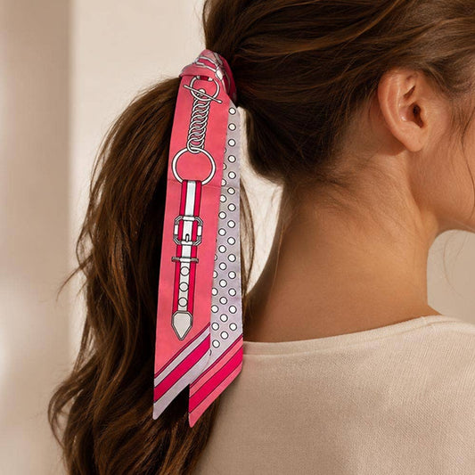 Person wearing a ponytail featuring a pink and white skinny scarf with a decorative design tied around it. 