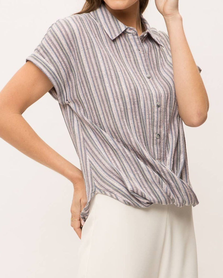 Woman wearing striped short sleeve button-up shirt with wrap front drape, collar and gold lurex detail.