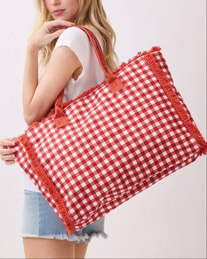 Woman holding a red and white checkered bag on a plain background.