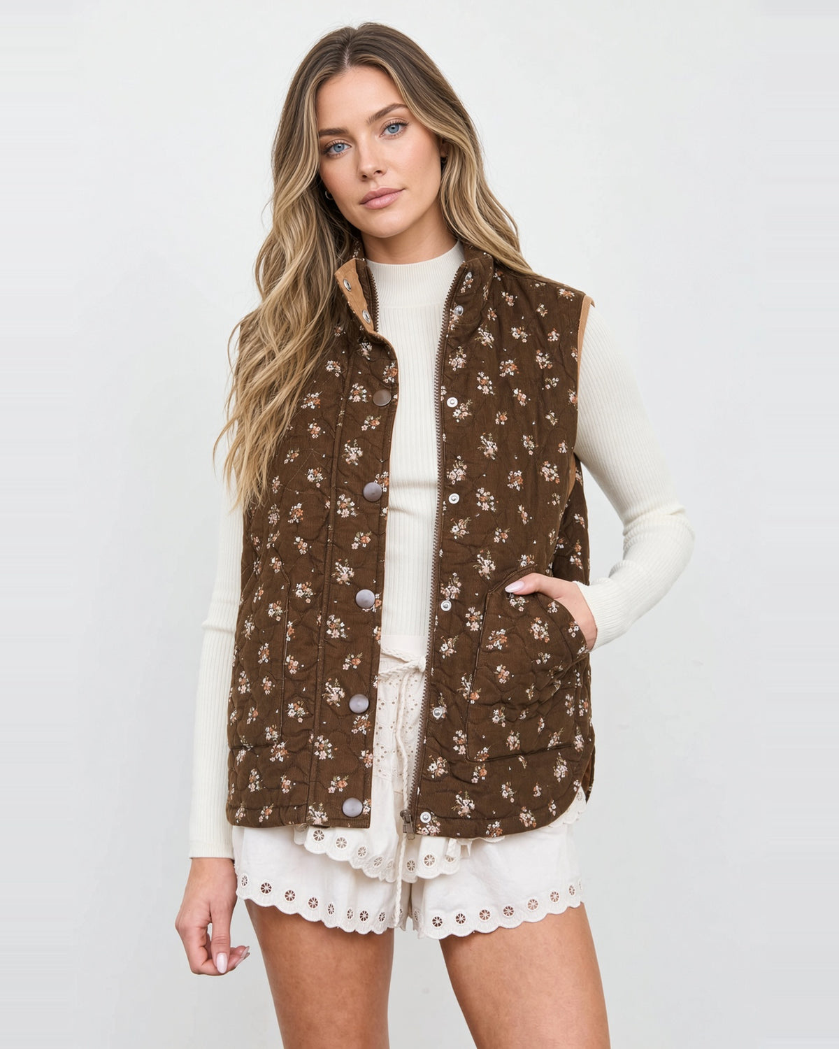 Model wearing a brown floral quilted vest with a stand collar, snap-front placket, and angled pockets.