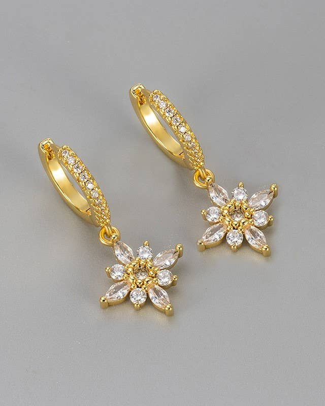 Gold hoop earrings with floral designs on a gray background.