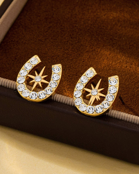 Gold horseshoe earrings with crystal star design on a brown velvet surface.