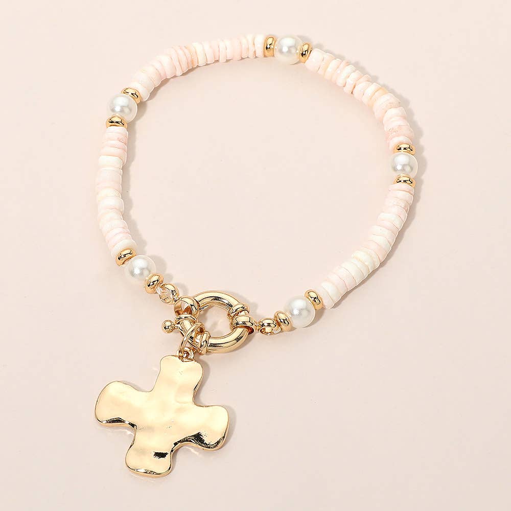 Bracelet with pink beads and a gold cross charm on a light pink background.