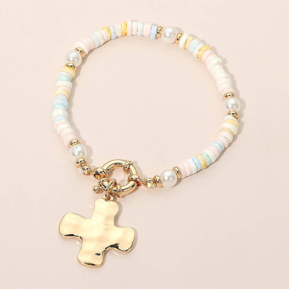 Bracelet with pastel beads and a gold cross charm on a beige background.