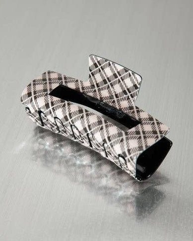 A large brown plaid hair clip photographed on a brushed metallic gray surface.